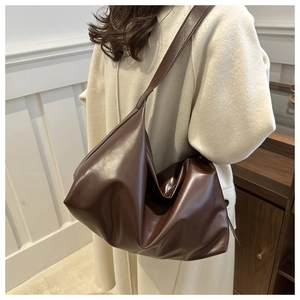 Detail of dark brown faux leather tote bag showing soft texture and large capacity on model