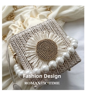 Detail of woven straw box bag featuring a large white daisy and pearl bead handle