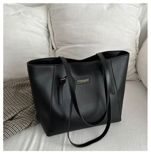 Detail of gold lettering on high-capacity black faux leather tote bag for office wear