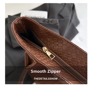 Detail of smooth gold zipper and woven leather texture on a vintage brown tote bag