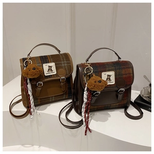 Detail of plaid backpacks with teddy bear charms and leather trim in retro college style