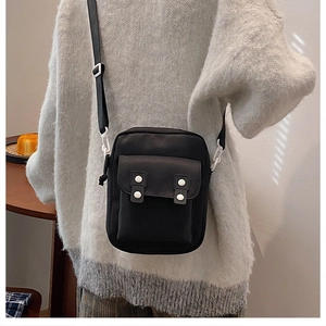 Détail d'un sac bandoulière en toile noire avec boucles blanches et bandoulière réglable