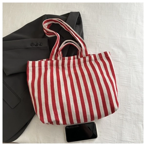 Flat lay of red and white striped canvas tote bag with dual straps and black blazer
