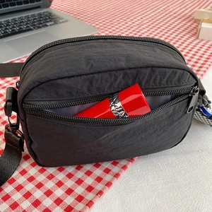 Waterproof nylon crossbody bag in black featuring multiple zippers and adjustable strap