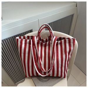 Close-up of a striped canvas tote bag with dual handles on a minimalist chair