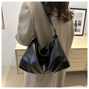 Close-up of black oversized tote bag showing soft leather drape on a model shoulder