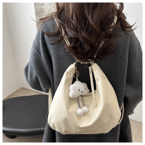 Detailed back view of a cream pleated tote bag with a white plush cloud charm