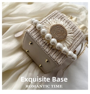 Detailed base view of straw bucket bag showing metal protective feet and pearl handle