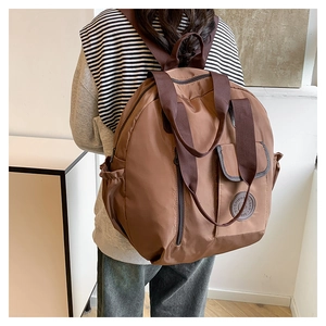 Detail view of brown water-resistant nylon backpack with multi-pocket design and dual handles