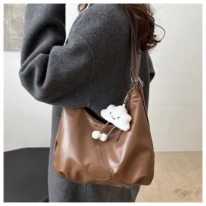 Detail of a brown pleated hobo tote bag with a cute white plush cloud charm accessory