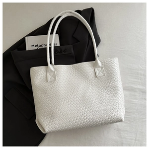 Detailed close-up of the woven leather texture on a white large capacity tote bag