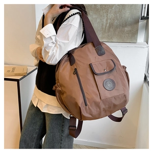 Detail of coffee brown nylon backpack featuring front magnetic flap and wide canvas straps