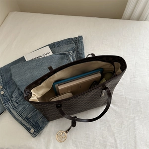 Brown monogram tote bag with gold M pendant showing spacious interior for tablets and books