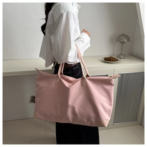 Pink waterproof nylon shoulder bag featuring leather handles and reinforced base detail
