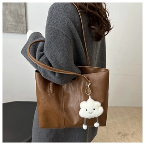 Brown large capacity tote bag with cute white plush cloud charm shown on model shoulder