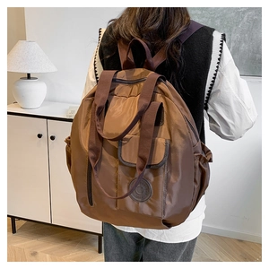 Brown nylon travel backpack detail showing large capacity side pocket and model wearing it