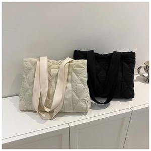 Close-up of quilted tote bags in cream white and black with elegant diamond stitching