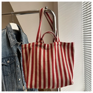 Detail of red and white striped canvas tote bag showing dual handles and natural texture