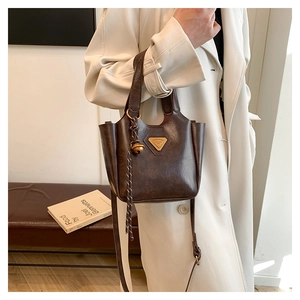Detail of vintage dark brown leather bucket bag with gold logo and bell charm accessory
