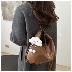 Detail of dark brown faux leather crescent bag with white fluffy cloud charm on model