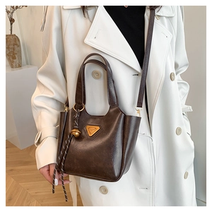 Detailed close-up of dark brown vintage bucket bag with triangle metal logo and round charm