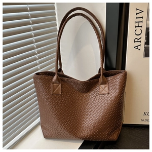 Detailed view of dark coffee woven leather texture and reinforced stitching on a tote bag