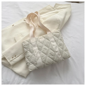 Close-up of beige quilted tote bag showing diamond stitch pattern on fabric