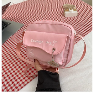 Dettaglio della borsa rosa con stampa di cucciolo e ciondolo mascotte abbinato