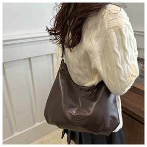 Detail of dark brown leather hobo bag with fashion logo embossing on soft material