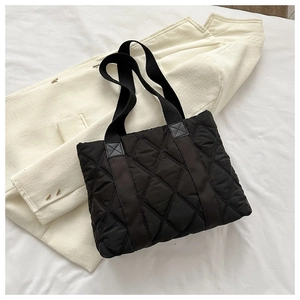Detail of black quilted tote bag texture on a white blazer background for daily use