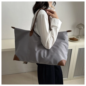 Detail of grey nylon tote bag with brown leather handles showing large capacity on model
