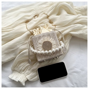Detail of straw woven bucket bag with pearl handle, sunflower decor and metal chain