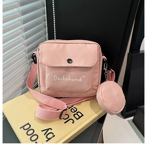 Detailed view of a pink nylon crossbody bag with small coin purse and adjustable strap