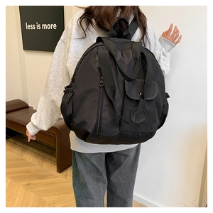 Detail of a black nylon backpack with magnetic front flap and top carry handles