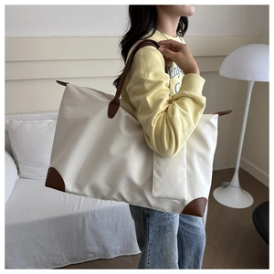 Detail of a minimalist waterproof tote bag with leather trim and matching mini pouch