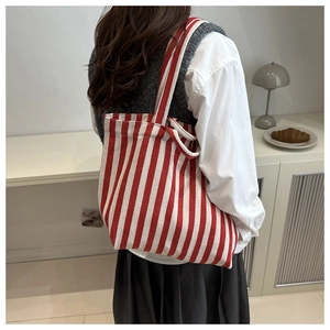 Detail of red and white striped canvas tote bag styled with a white shirt and vest