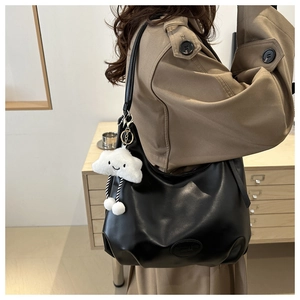 Detail of black matte leather hobo bag featuring embossed logo and plush cloud charm