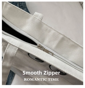 Detail shot of smooth silver zipper closure and thick canvas texture on white tote bag