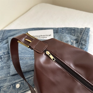 Large dark coffee leather tote bag with vintage metal buckle on a blue denim jacket