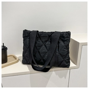 Close-up of black quilted nylon tote bag with rhombus pattern on minimalist storage unit