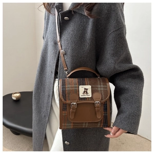 Detail of British style brown plaid crossbody bag with metal buckles and leather trim