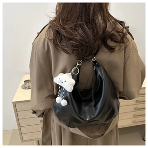 Detail of black soft PU hobo bag with a cute white plush cloud charm on a wide shoulder strap