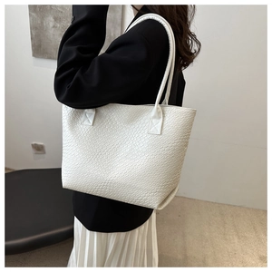 Detail of white woven texture on a large capacity tote bag worn on shoulder