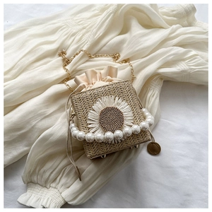 Detail of straw bucket bag with large white sunflower, pearl handle and gold chain strap