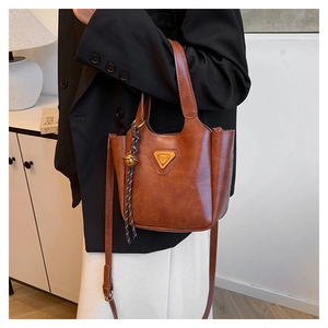 Close-up of brown bucket bag showing fine leather texture and golden triangle hardware