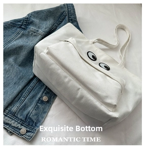 Detail of white canvas tote bag with large eye pattern and functional front zipper pocket
