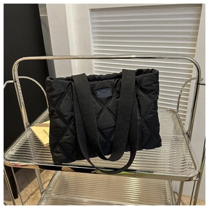 Macro detail of black quilted puffer tote bag featuring classic large diamond pattern