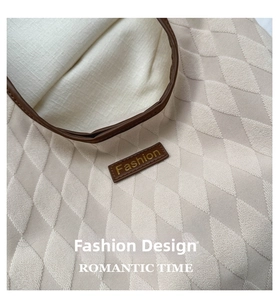 Detail of quilted rhombic texture and leather brand patch on beige tote bag