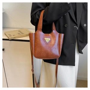 Detail of vintage brown bucket bag showing the golden triangular logo and leather texture