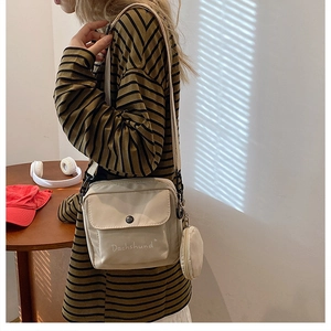 Detail of off-white nylon crossbody bag featuring a front flap pocket and round coin purse